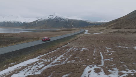 seguimiento de un disparo de drone de un coche rojo moviéndose por la carretera en el frío paisaje de islandia