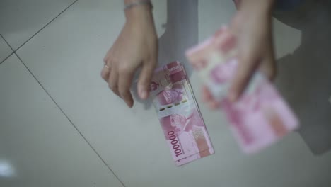 female hands counting by dropping money on floor with change focus