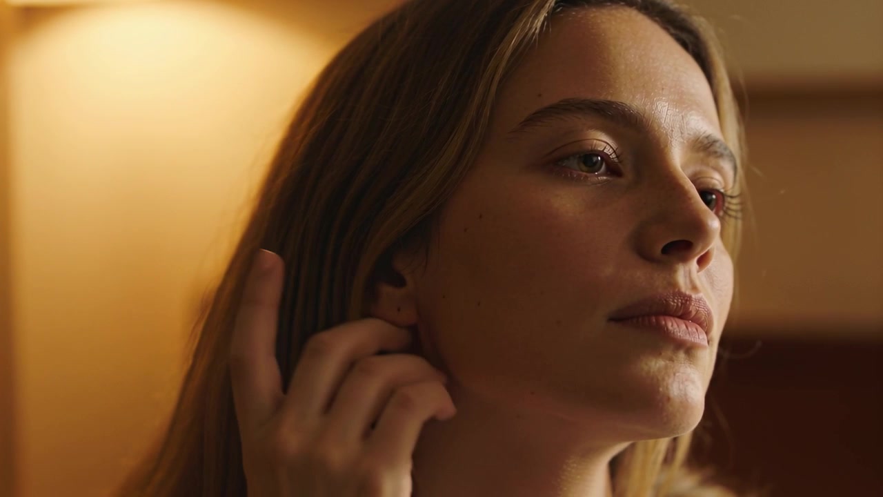 Respirando, una donna con un top chiaro abbassa il mento, si sistema i capelli, tiene una lampada da comodino e si sistema.
