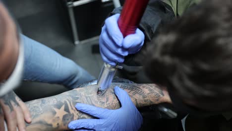 maestro del tatuaje quitando el tatuaje en el brazo del cliente