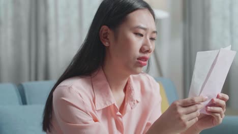 close up of asian woman looking at the bill on hand and checking money on the purse before shaking her head