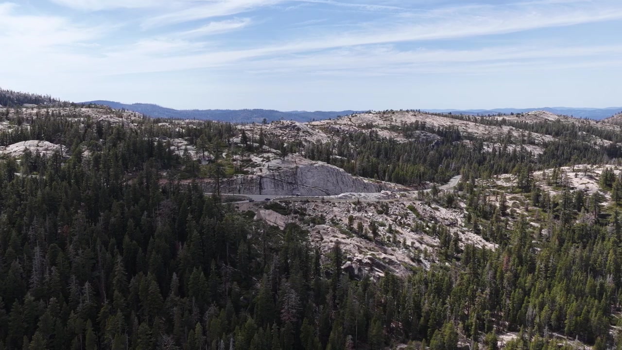 Riprese aeree che mostrano il paesaggio roccioso e granitico e la fitta pineta che circonda il bacino idrico di Silver Lake nelle montagne della Sierra Nevada vicino a Pioneer, California, in una giornata di sole splendente