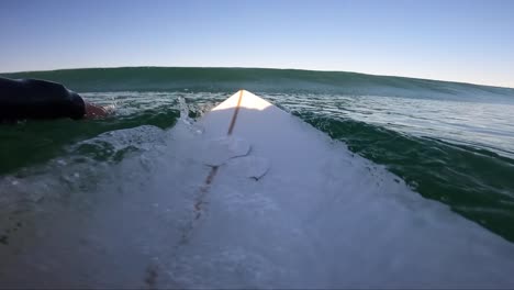 Slow-motion-shot-of-a-surfboard-surfer-duck-dives-under-a-wave-out-in-the-surf