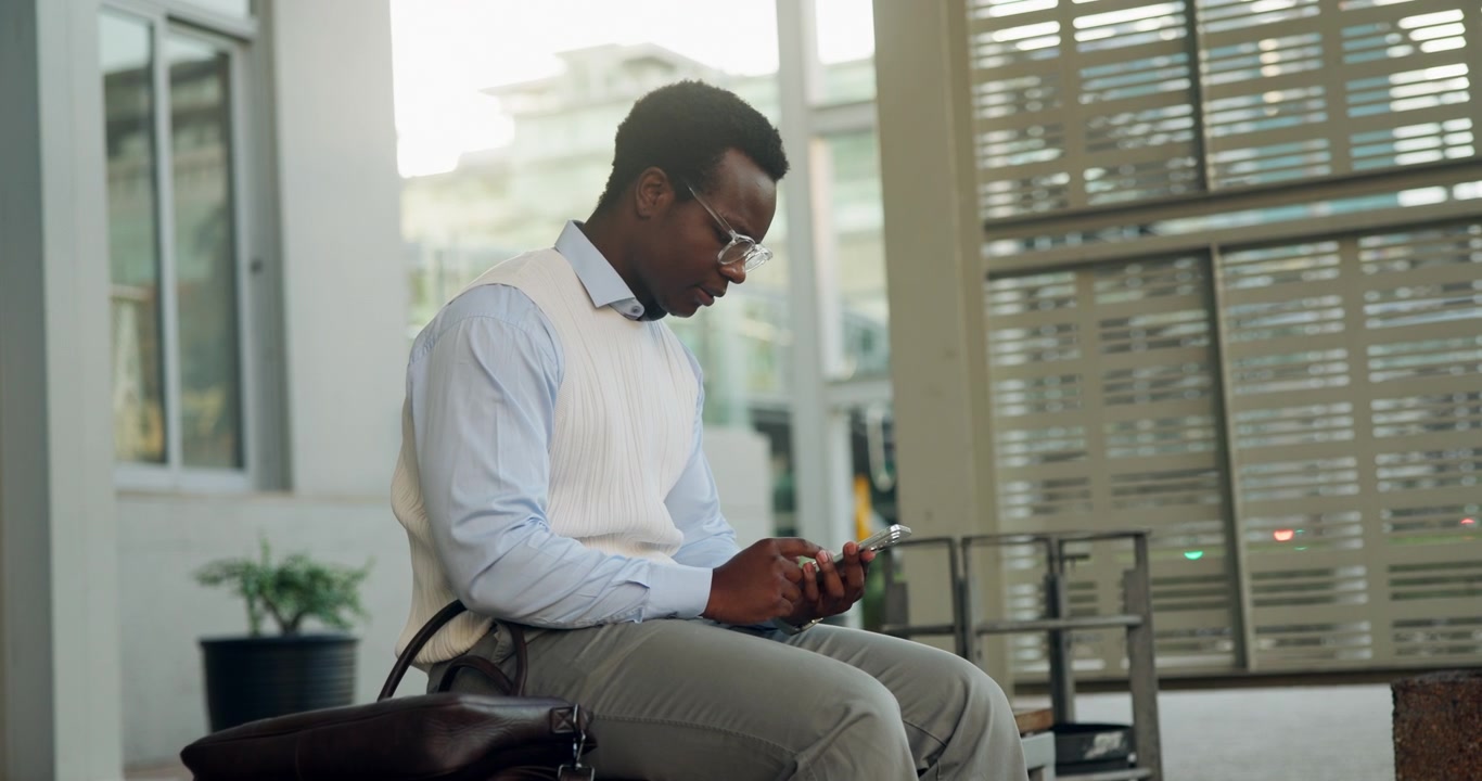 Young Professional Man Using Smartphone While Sitting Outside Office Building