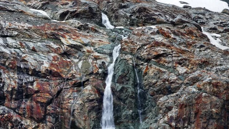 Cascata che scorre da un ghiacciaio lungo una parete rocciosa
