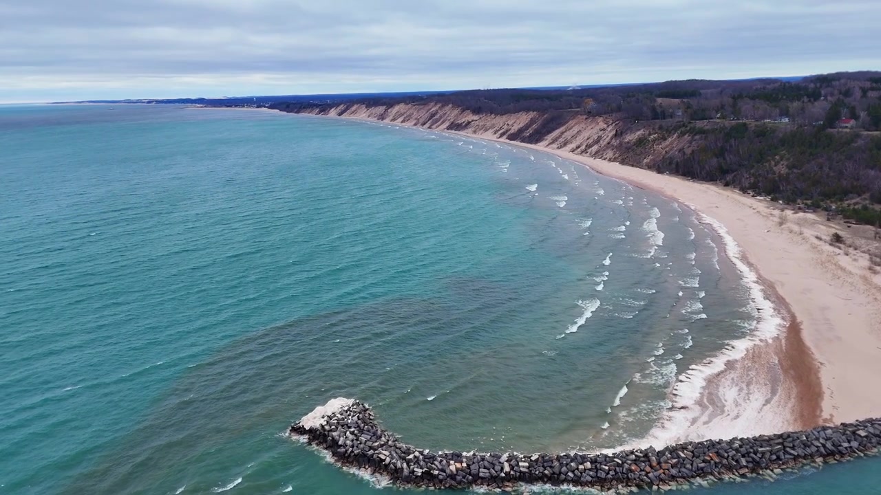 Kustlijn van Lake Michigan met pier en zandstrand op een bewolkte dag nabij Ludington, Michigan, VS.