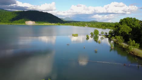vuela hacia abajo aterrizando un dron en un lago en la temporada de primavera con árboles de hojas verdes alrededor de la naturaleza con cielo azul con nubes blancas paisaje en una zona rural en azerbaiyán refleja el cielo en agua hermosa