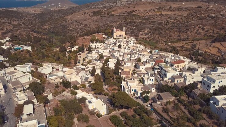 Ripresa aerea con drone in lento allontanamento che rivela il villaggio isolano di Lefkes, Grecia.