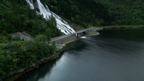 travelling car drives over roads in norway next to a waterfall