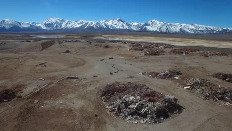 Trash-and-garbage-are-piled-in-a-local-refuse-dump-with-the-beauty-of-California\'s-Sierra-Nevada-mountains-in-the-background