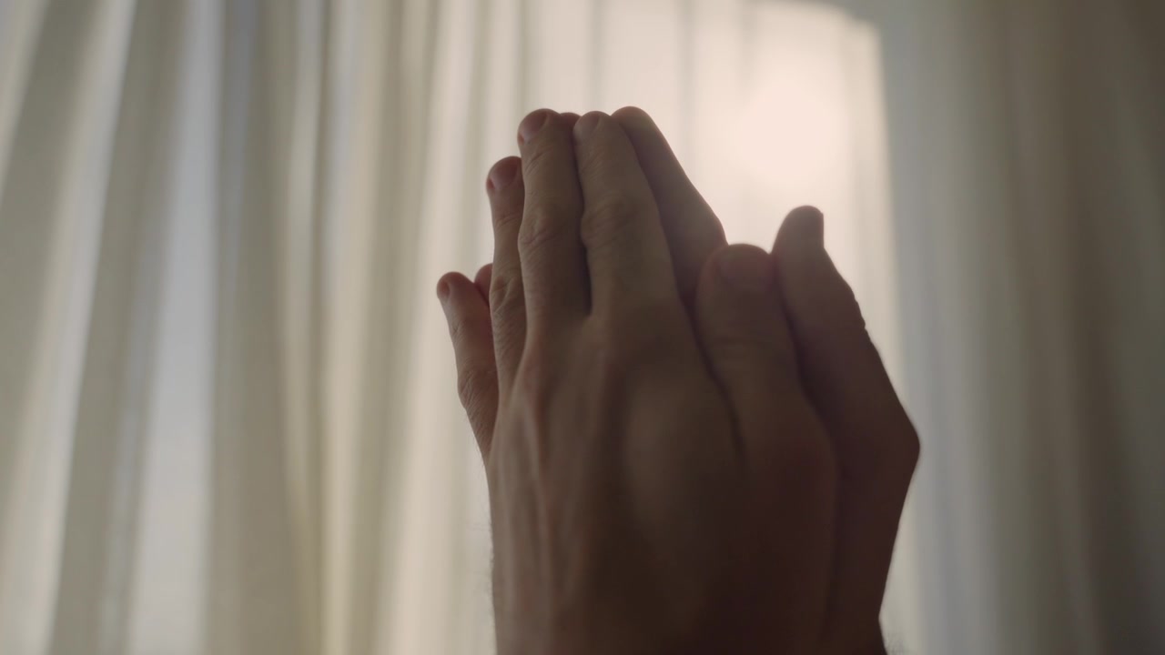 Silhouette di mani maschili unite in un gesto di preghiera contro una finestra luminosa. Desiderio o richiesta a Dio per una benedizione. Emozione positiva, risveglio religioso o illuminazione. Persona che giunge le mani.