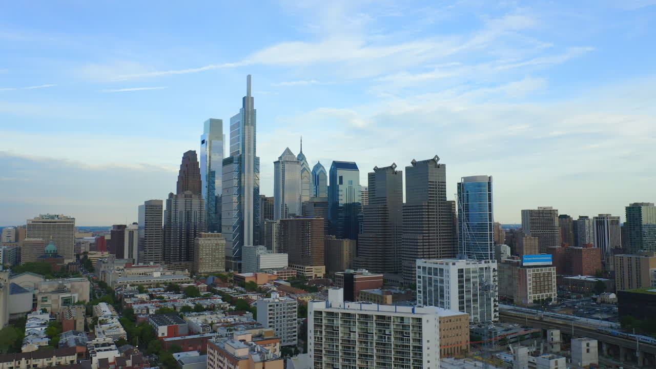 Aerial drone flying right through Philadelphia city skyline showcasing Comcast Technology Center and tall east coast skyscrapers and buildings