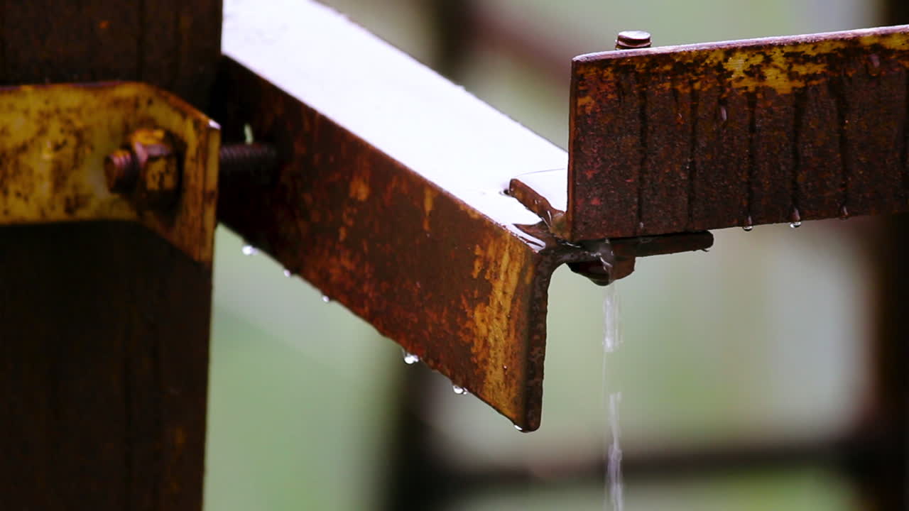 Close-up of rainwater dripping from rusty metal structure. Great for concepts of decay, corrosion, weather and industrial textures