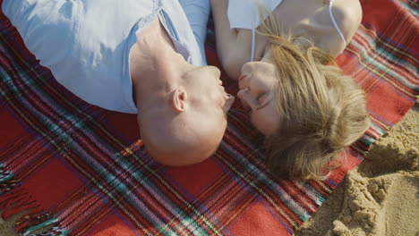 top view of couple lying on plaid at beach