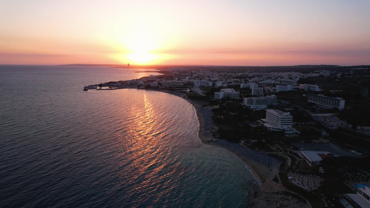 Cena mágica de drone de um pôr do sol dourado e quente sobre o horizonte em Ayia Napa, Chipre, com reflexo na água calma do mar.