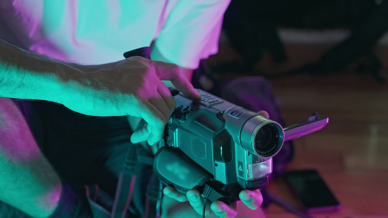 Person Operating Vintage Camcorder with Neon Lighting