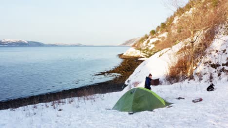 aerial view of camper walking outside his tent at winter