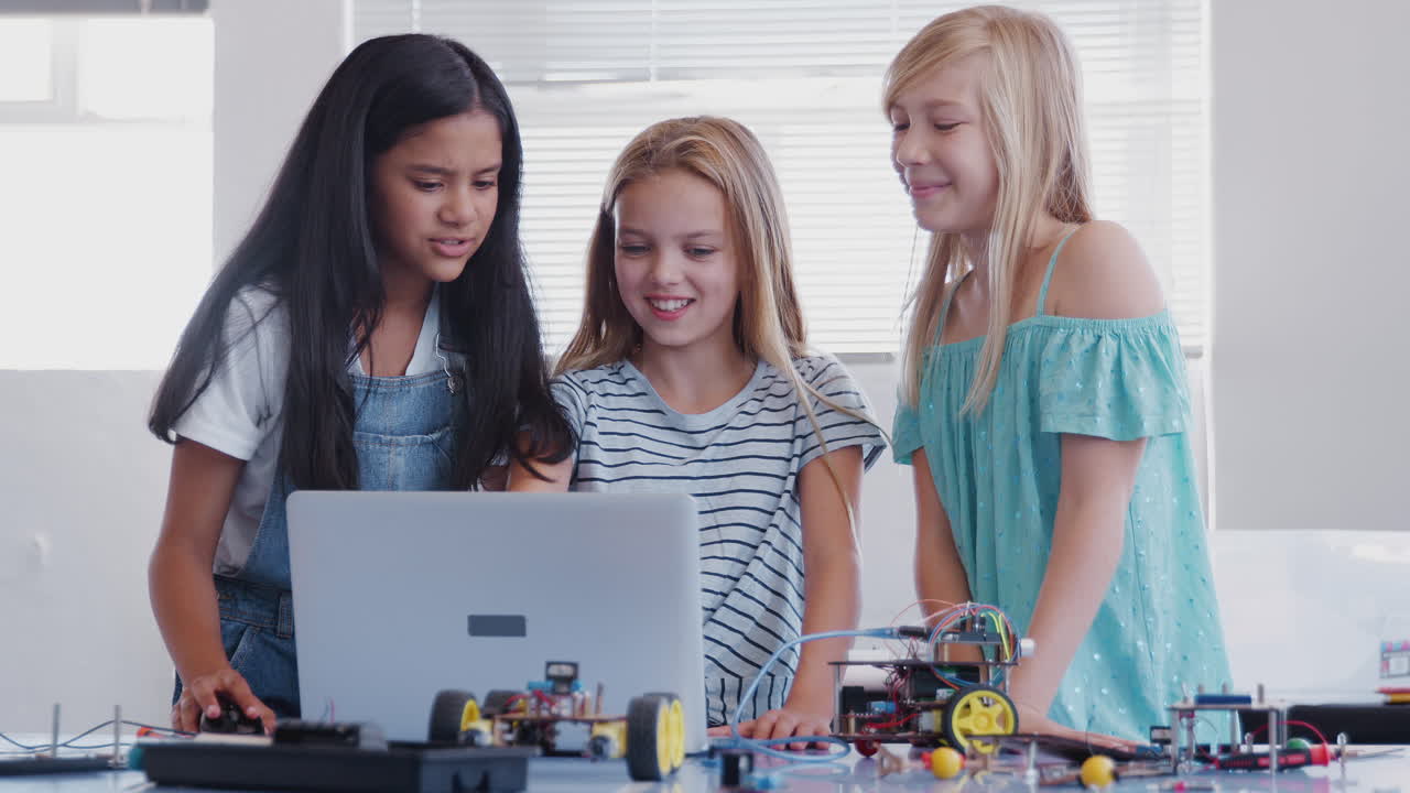 Three Female Students Building And Programing Robot Vehicle In After School Computer Coding Class