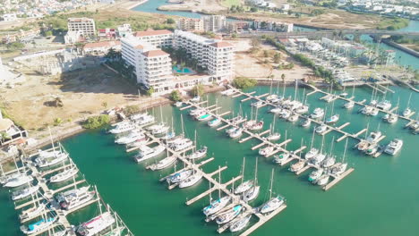 Jib-down-of-boats-docked-in-harbor-in-front-of-luxurious-hotel-in-sunny-Mexico