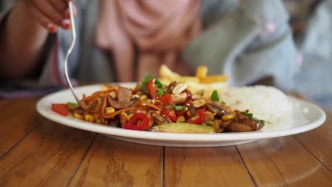 woman eating asian stir-fry with rice