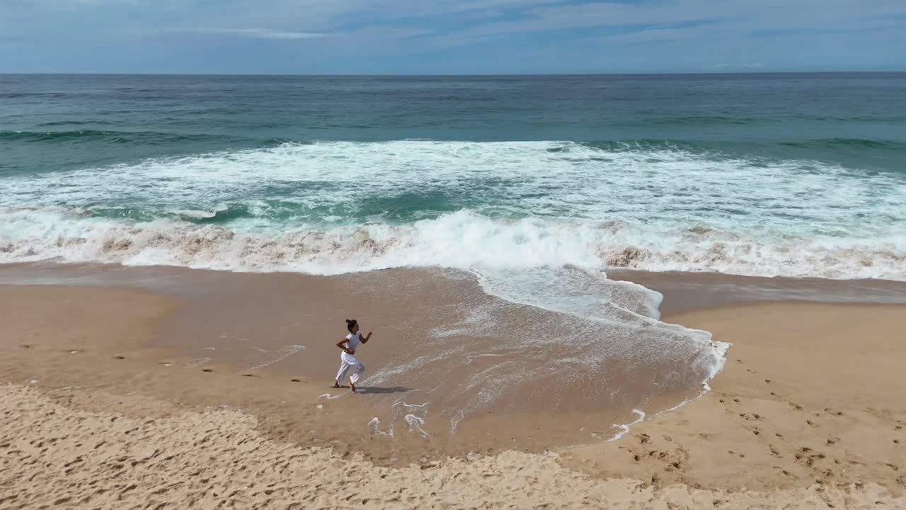 Woman running on a sandy beach by the ocean