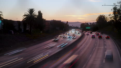 lapso de tiempo del tráfico de la autopista ocupada con desenfoque de movimiento en los ángeles en la hora dorada