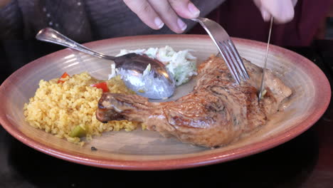 person eating a chicken dinner with rice and coleslaw