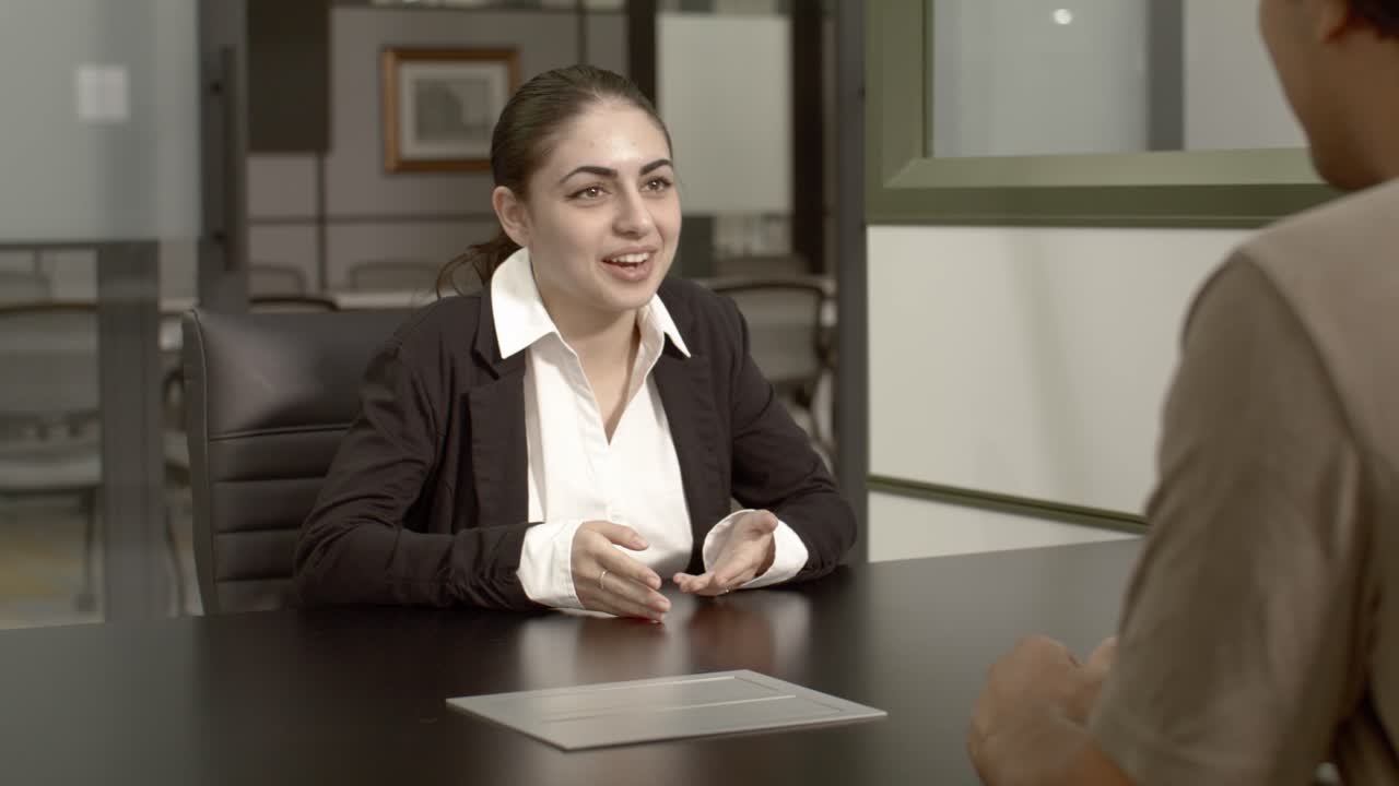 Arab American female in her 20's with talking with a man in an office setting with dolly video shot moving right to left