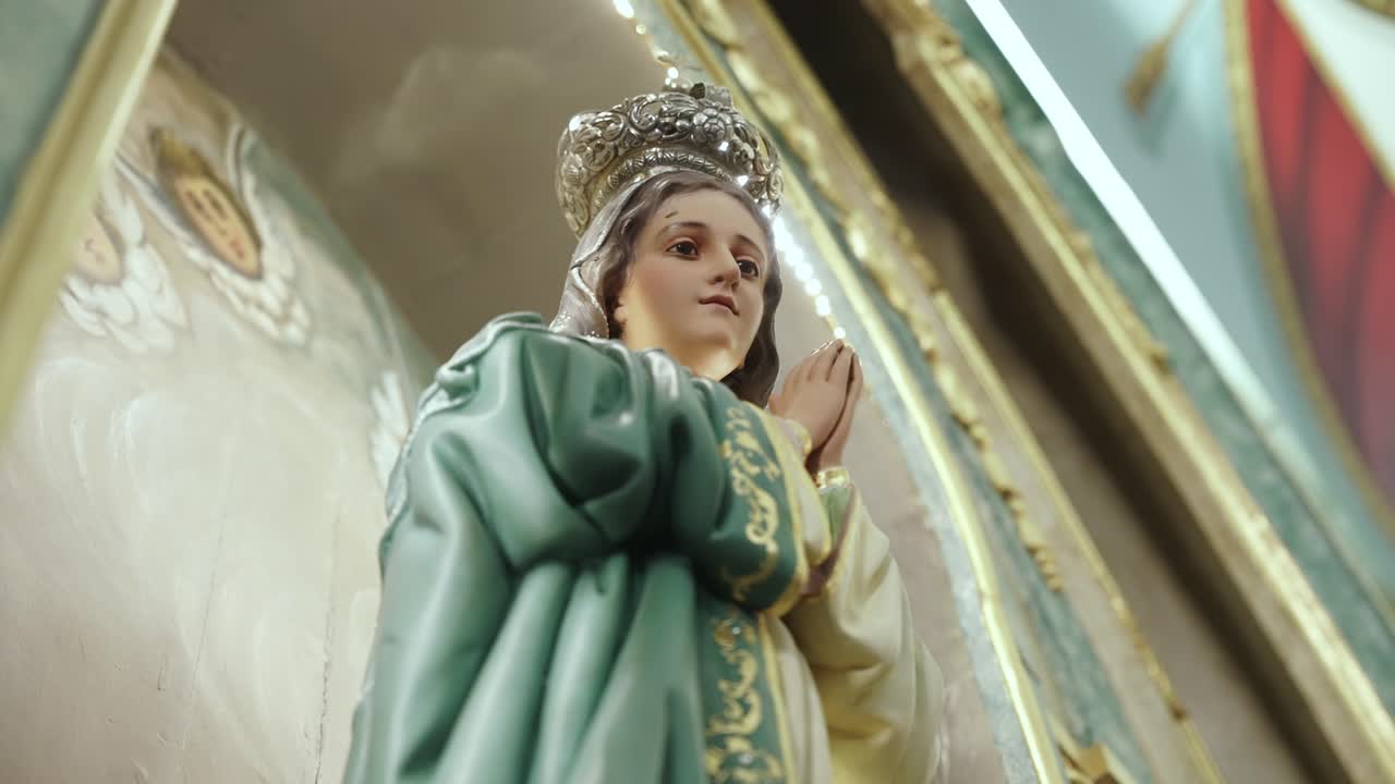 close up of crowned virgin mary statue in prayerful pose inside church
