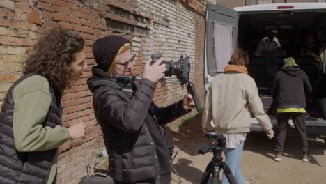 two production co workers setting up a camera in the street and other two workers taking material for a recording from a van 2