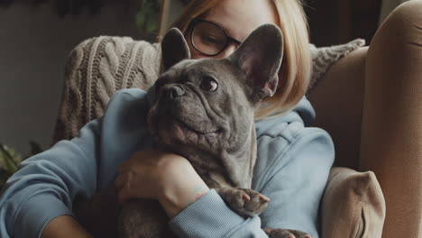 close up view of red haired woman caresses her bulldog dog while they are sitting on the sofa in the living room at home 3