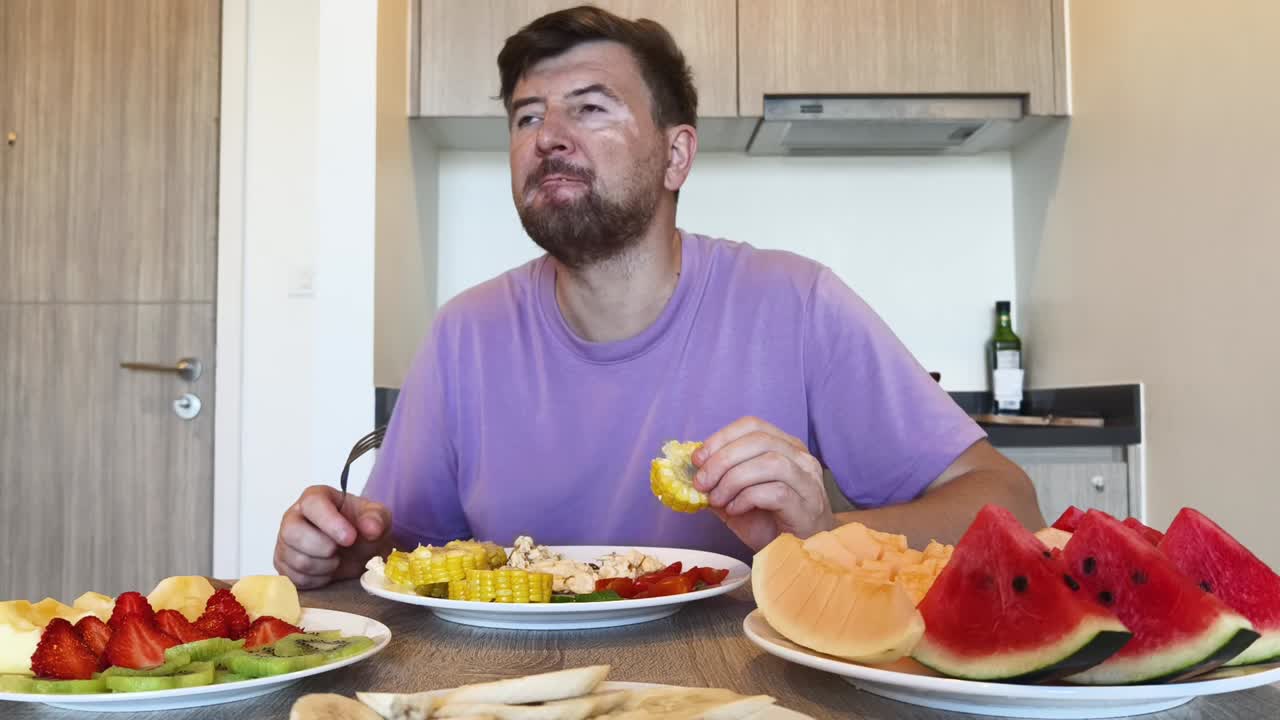 Man eating fruit and corn at a table