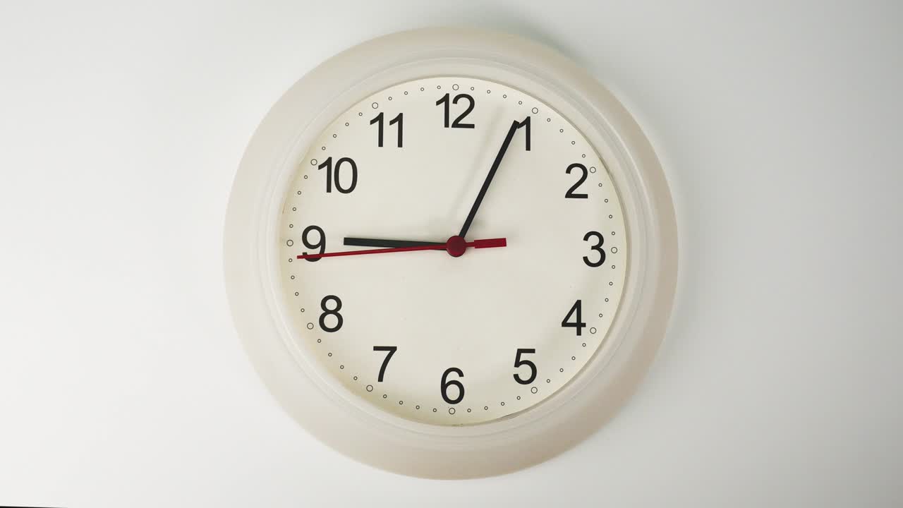 Orologio da parete bianco che indica le 9 e 5 minuti.