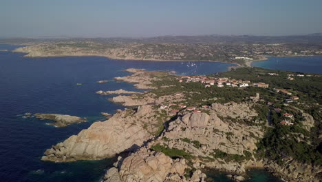 Drone-shot-flying-over-a-rocky-coastline-with-holiday-houses-on-it-in-north-Sardinia