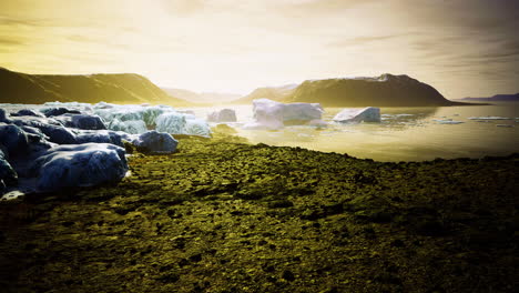 stunning view of icy landscape with mountains and calm waters at sunset