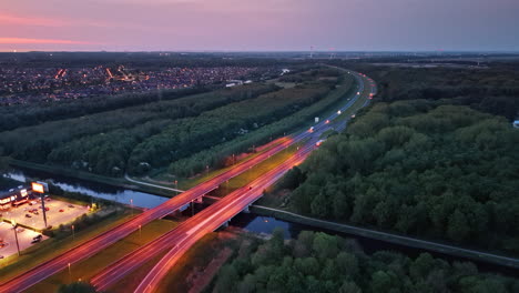 Dutch roads at dusk. A sunset illuminates a highway winding through the Netherlands' lush suburbs, blending urban and natural beauty