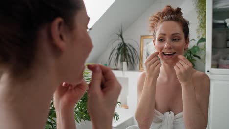 caucasian woman flossing teeth in the bathroom.