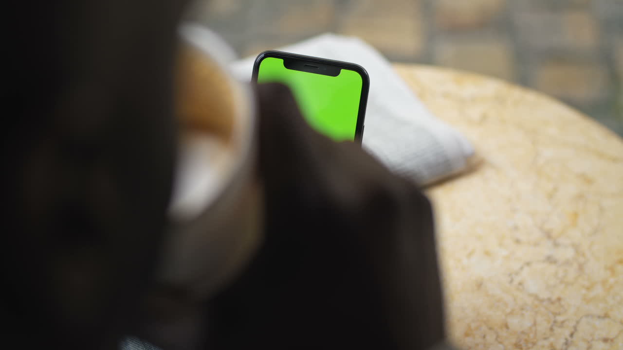 Person using phone with green screen while drinking coffee