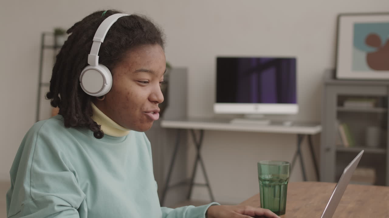 African Girl Having Video Talk Using Laptop and Headphones