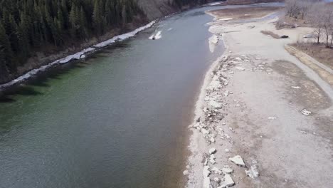 a boat motors down a river with dirty ice along its banks