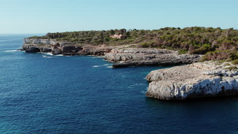 calm and blue sea with rocky shore in cala mondragó beach, mallorca, spain