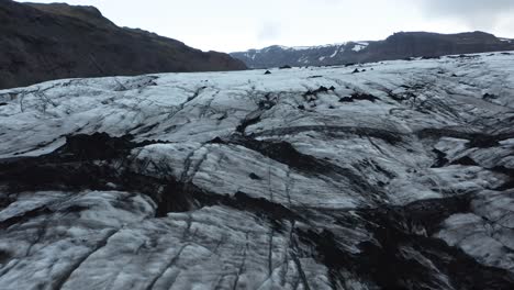 dark frozen ice at bottom of sólheimajökull glacier in iceland, aerial