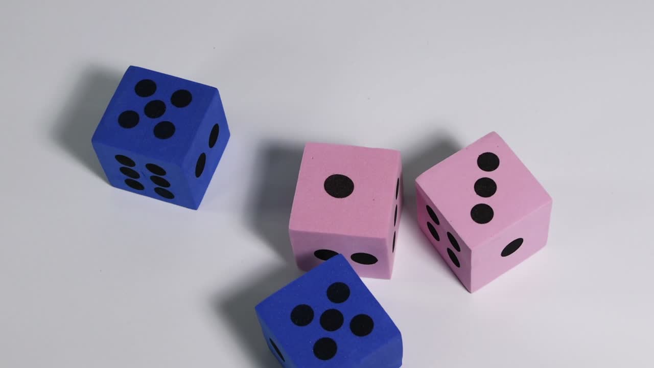 Blue, pink, and red dice tumble and settle on a smooth white background.
