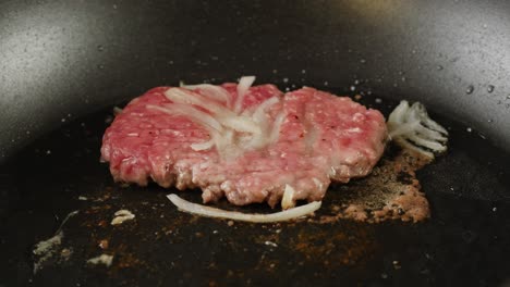 cooking a hamburger patty in a frying pan