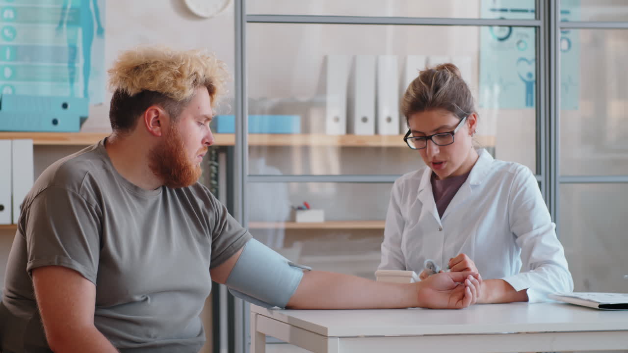 doctora midiendo la presión arterial de un hombre con sobrepeso en una clínica