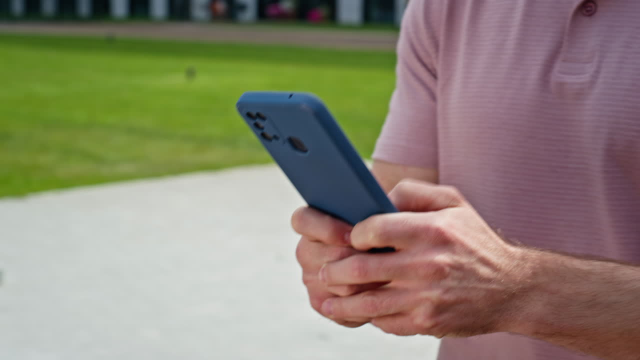 Man using smartphone going city street alone closeup. Unknown guy hands typing