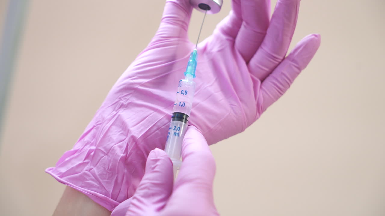 Close-up view on a cosmetologists hands in gloves holding syringe with needle for rejuvenating facial injections.