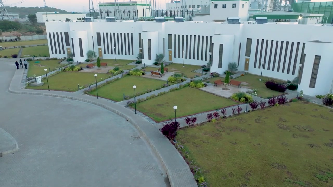 Drone trækker sig tilbage fra en have for at afsløre et kraftværkskompleks, Pakistan.