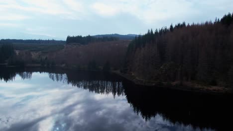 aerial drone flying above peaceful calm lake of loch lochy, water reflection, rising reveal forest landscape