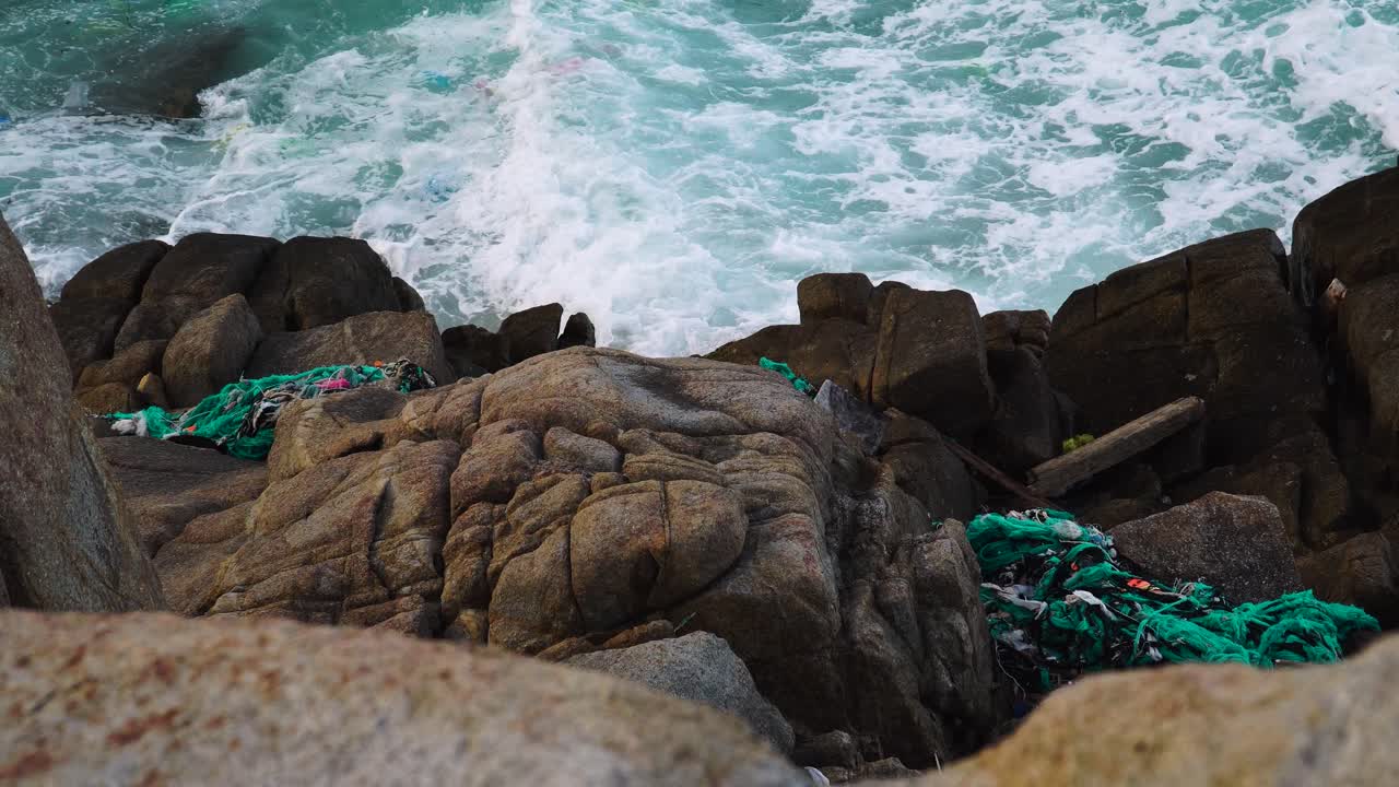 해안 바위에 쌓여 바다 파도에 표류하는 쓰레기, 수질 오염 위기